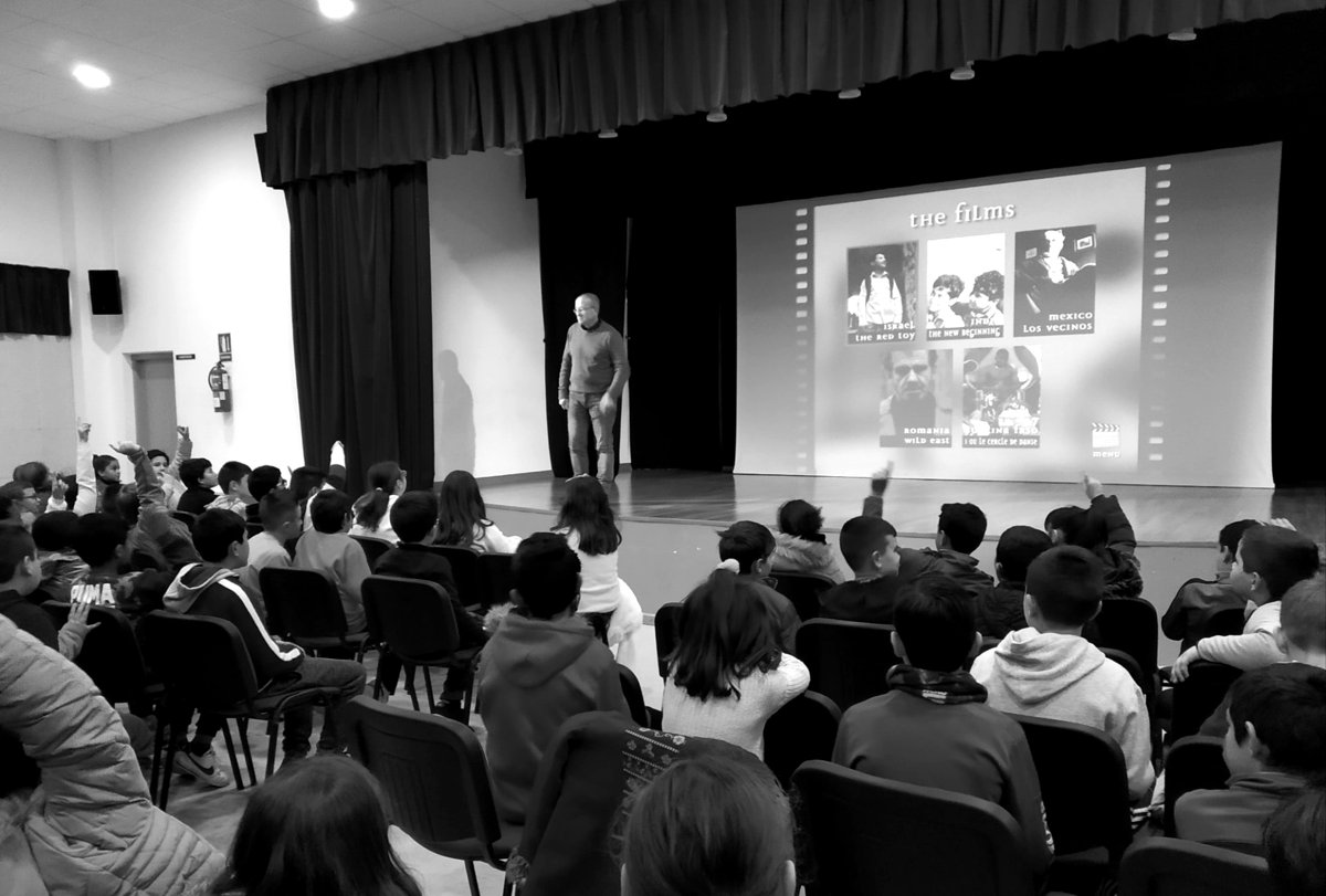 Jóvenes en un salón de actos escuchando una charla con proyección